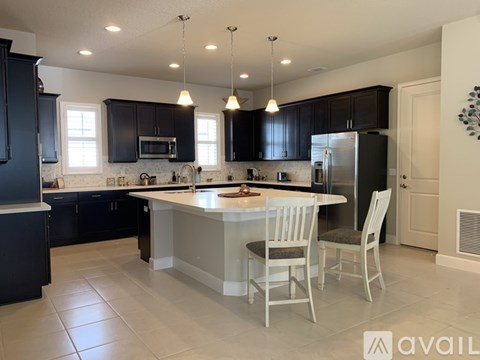 A kitchen with a large island and chairs.