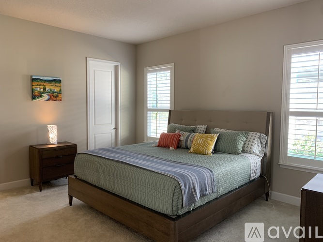 A bedroom with a large bed and a painting on the wall.
