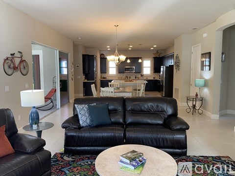A living room with a black leather couch and a bicycle hanging on the wall.