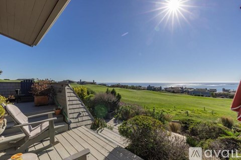 A sunny day with a clear blue sky and a view of the ocean from a patio.