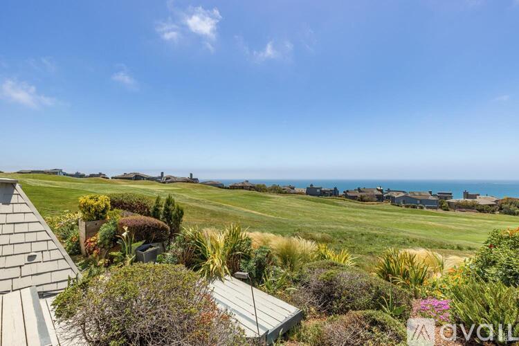 A house with a view of the ocean is surrounded by greenery.