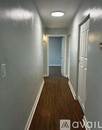 A long hallway with white walls and wood flooring.