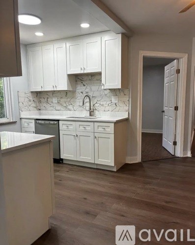 A kitchen with white cabinets and a marble backsplash.