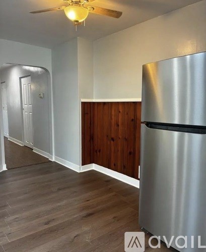 A kitchen with a stainless steel refrigerator and wooden paneling on the wall.