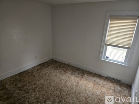 A room with a carpeted floor and a window with blinds.