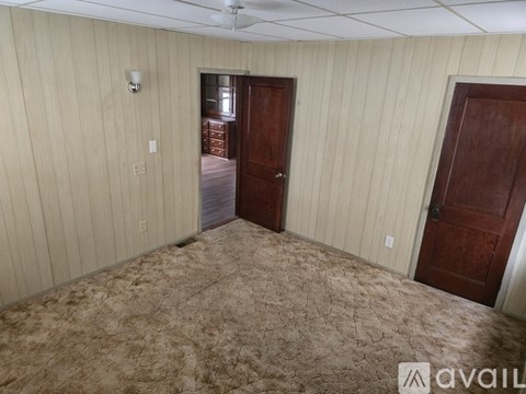 A room with a carpeted floor and two doors.