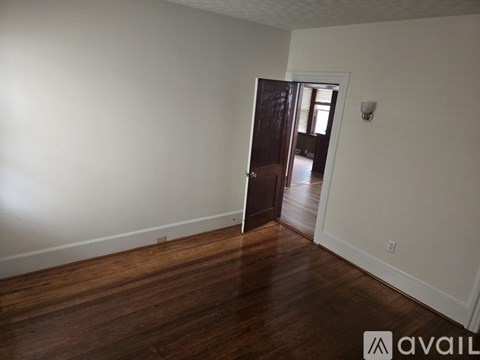A room with wooden floors and a door leading to another room.