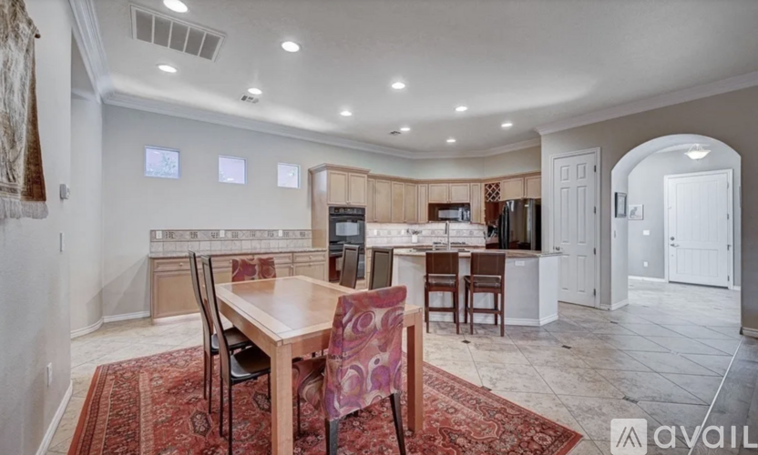 A dining room with a table set for two and a kitchen area in the background.