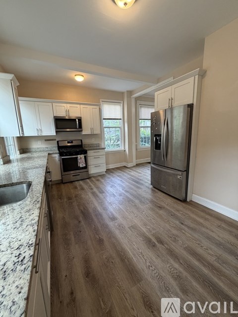 A kitchen with a refrigerator, sink, and cabinets.