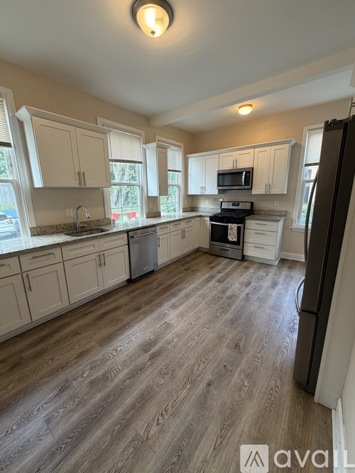 A kitchen with wooden floors and white cabinets.