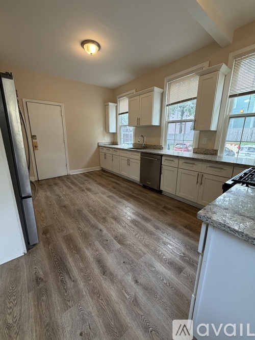 A kitchen with wooden flooring and white appliances.