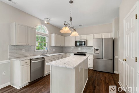 A kitchen with white cabinets and a marble island.