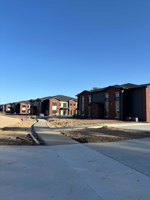 A row of new houses with a concrete pathway in front.