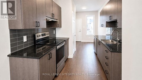 A modern kitchen with dark countertops and wooden cabinets.