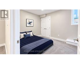 A bedroom with a bed, pillows, and a framed picture on the wall.