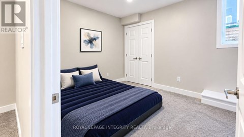 A bedroom with a bed, pillows, and a framed picture on the wall.