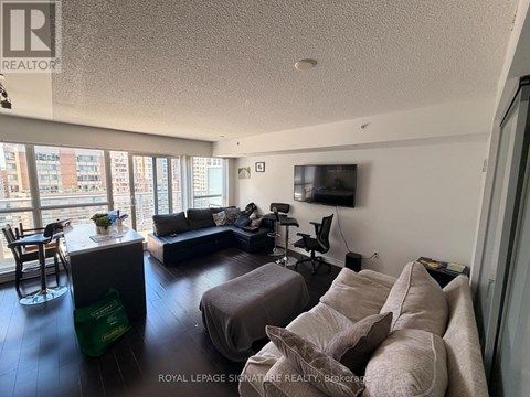 A living room with a grey couch and a flat screen TV mounted on the wall.