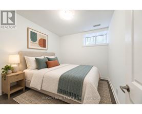 A bedroom with a bed, nightstand, and a painting on the wall.