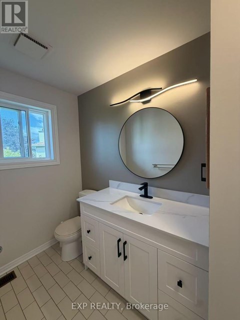 A bathroom with a white sink and a round mirror.
