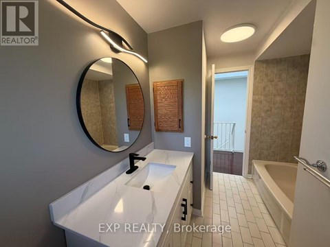 A bathroom with a white sink and a round mirror.
