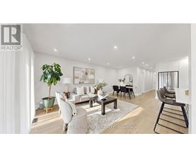 A well-lit, modern living room with a dining area and a kitchen in the background.