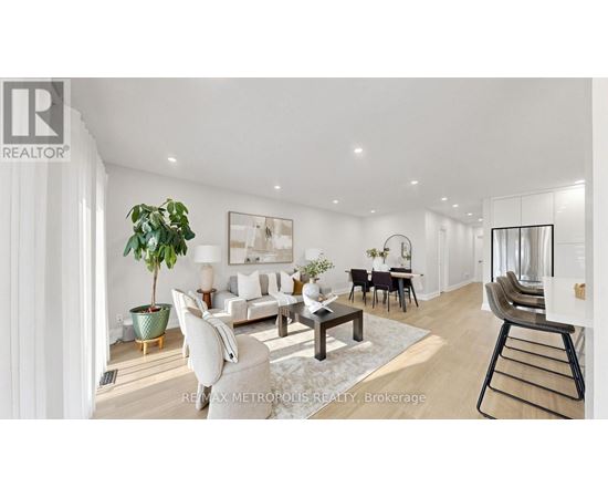 A well-lit, modern living room with a dining area and a kitchen in the background.