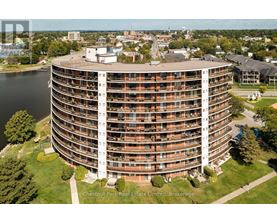 A large round building with a lot of windows and balconies sits in the middle of a grassy area.