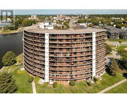 A large round building with a lot of windows and balconies sits in the middle of a grassy area.