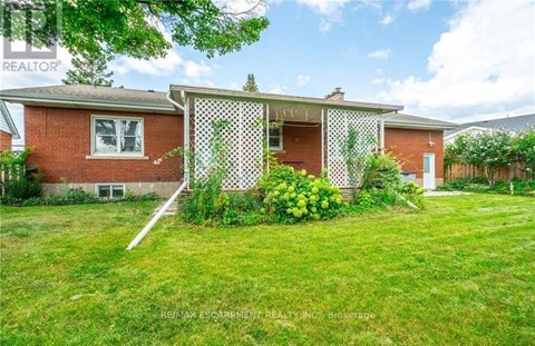 A red brick house with a white picket fence and green grass in front.