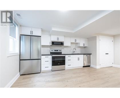 A white kitchen with a refrigerator, oven, microwave, and cabinets.