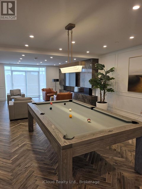 A pool table in a room with a light brown herringbone patterned floor.