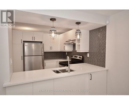 A modern kitchen with white cabinets and a stainless steel refrigerator.