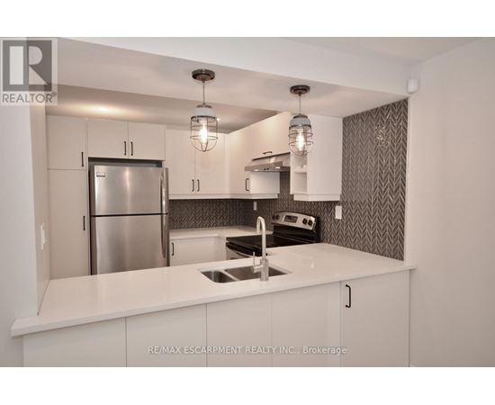 A modern kitchen with white cabinets and a stainless steel refrigerator.