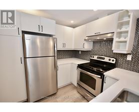A kitchen with a stainless steel refrigerator and a black stove top oven.