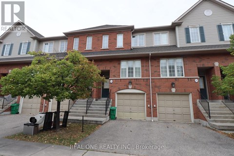 A two-story brick house with a garage and a tree in front.