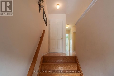 A hallway with a white door and a wooden staircase.
