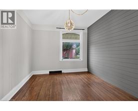 A room with wooden flooring and a window showing a red building outside.