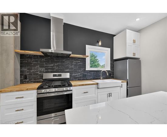 A modern kitchen with a black wall and a stove top oven.