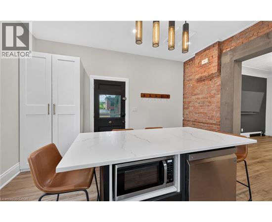 A modern kitchen with a white table and brown chairs.