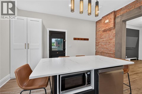 A modern kitchen with a white table and brown chairs.
