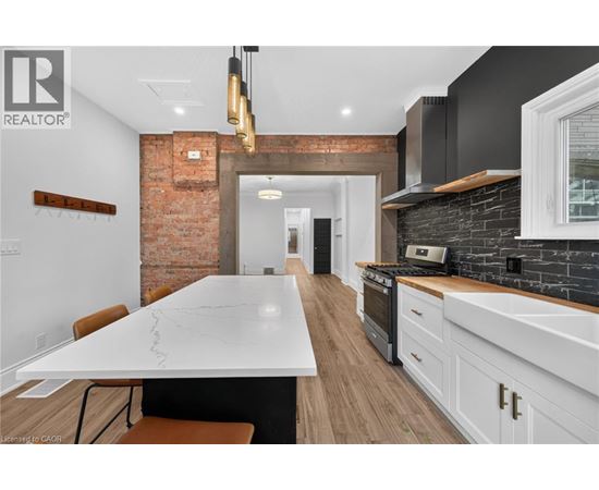 A modern kitchen with a large island and a brick wall.