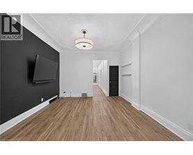 A spacious room with wooden flooring and a flat-screen TV mounted on the wall.