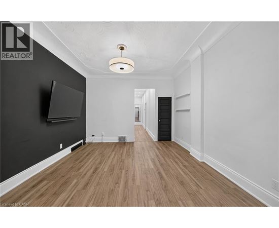 A spacious room with wooden flooring and a flat-screen TV mounted on the wall.