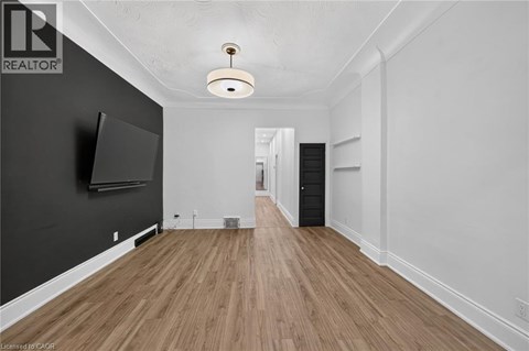A spacious room with wooden flooring and a flat-screen TV mounted on the wall.