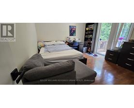 A bedroom with a bed, dresser and chair.