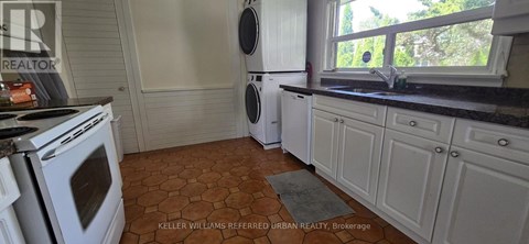 A kitchen with a white oven and a tiled floor.