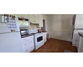 A kitchen with white appliances and brown flooring.