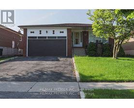 A house with a garage door and a tree in front.