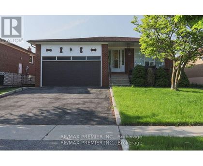 A house with a garage door and a tree in front.
