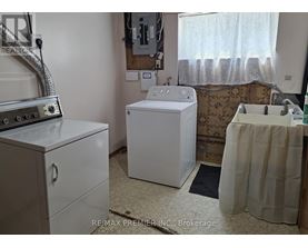 A white washing machine sits in a small laundry room.